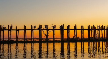 Tanımlanamayan insanlar gün batımında Myanmar 'da U-Bein köprüsünde yürürler. U-Bein köprüsü dünyanın en uzun tik köprüsü, Amarapura, Myanmar