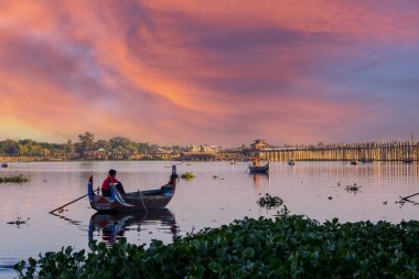 Amarapura, Myanmar - 22 Kasım 2016: Myanmar 'da gün batımında kimliği belirsiz kişiler U Bein köprüsünde yürüyor. U Bein köprüsü dünyanın en uzun meşe köprüsü..