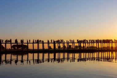 Amarapura, Myanmar - 22 Kasım 2016: Myanmar 'da gün batımında kimliği belirsiz kişiler U Bein köprüsünde yürüyor. U Bein köprüsü dünyanın en uzun meşe köprüsü..