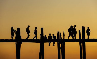Amarapura, Myanmar - 22 Kasım 2016: Myanmar 'da gün batımında kimliği belirsiz kişiler U Bein köprüsünde yürüyor. U Bein köprüsü dünyanın en uzun meşe köprüsü..