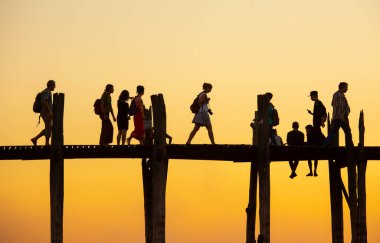 Amarapura, Myanmar - 22 Kasım 2016: Myanmar 'da gün batımında kimliği belirsiz kişiler U Bein köprüsünde yürüyor. U Bein köprüsü dünyanın en uzun meşe köprüsü..