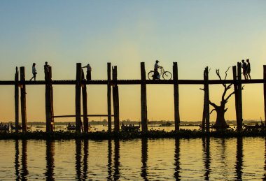 Amarapura, Myanmar - 22 Kasım 2016: Myanmar 'da gün batımında kimliği belirsiz kişiler U Bein köprüsünde yürüyor. U Bein köprüsü dünyanın en uzun meşe köprüsü..