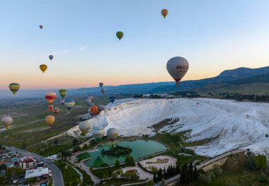 Pamukkale, Denizli 'de güneş doğarken sıcak hava balonları ve doğal travertin havuzları