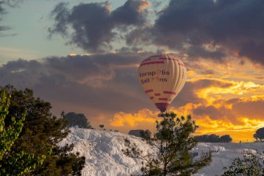 Denizli, Türkiye, 1 Mayıs 2023: Pamukkale 'de güneş doğarken sıcak hava balonları ve doğal travertin havuzları, 