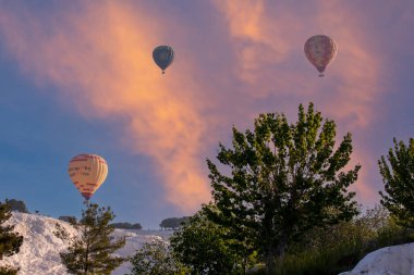 Denizli, Türkiye, 1 Mayıs 2023: Pamukkale 'de güneş doğarken sıcak hava balonları ve doğal travertin havuzları, 