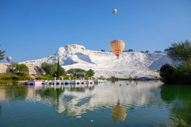 Denizli, Türkiye, 1 Mayıs 2023: Pamukkale 'de güneş doğarken sıcak hava balonları ve doğal travertin havuzları, 