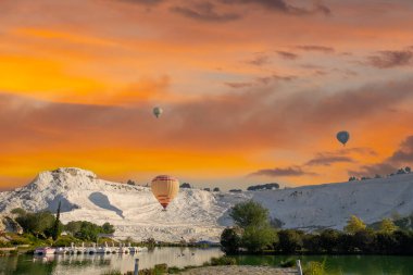 Denizli, Türkiye, 1 Mayıs 2023: Pamukkale 'de güneş doğarken sıcak hava balonları ve doğal travertin havuzları, 