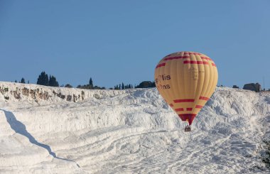 Denizli, Türkiye, 1 Mayıs 2023: Pamukkale 'de güneş doğarken sıcak hava balonları ve doğal travertin havuzları, 