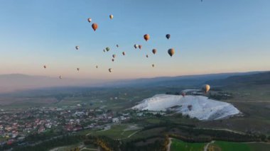 Pamukkale 'de güneş doğarken sıcak hava balonları ve doğal travertin havuzları, 