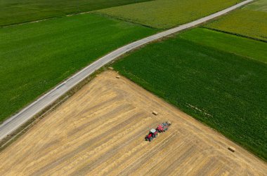 Çiftlik arazisi, çiftçiler tarım arazisinde traktörle çalışıyorlar.,