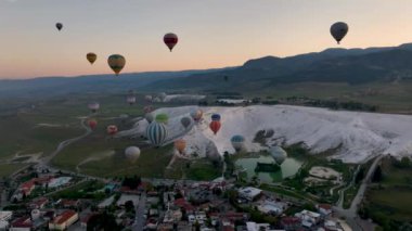 Pamukkale 'de güneş doğarken sıcak hava balonları ve doğal travertin havuzları, 