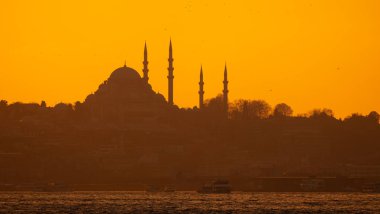 Gün batımında Süleyman Camii 'nin silueti. Altın gökyüzü ve bulutlar.