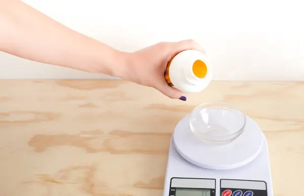 stock image Woman weighing grams of soy candle essence in a weighing machine. Sustainable, organic candles, vegetable waxes. Small businesses, female businesses.