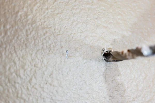 Stock image Selective focus on point of penetration of a drill bit making a pilot hole in drywall. High quality photo