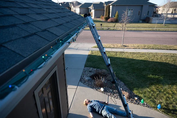 Concept of falling danger involved with hanging Christmas lights on the roof and falling from heights