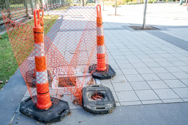 Open cover on a sidewalk access panel with hazard cones and fencing. High quality photo