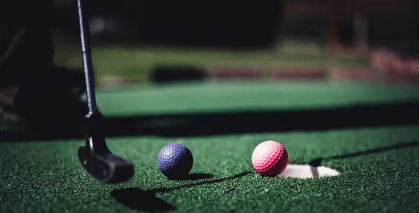 Mini golf game with several colored balls in the way of a putter lined up. High quality photo