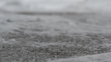 Karla kaplı beton üzerinde kaya tuzu eritmenin makro seviye yakın çekim görüntüsü. Yüksek kalite 4k görüntü
