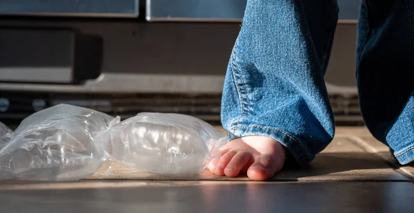 Focus on feet of a child standing on top of bubble wrap that has been popped. . High quality photo