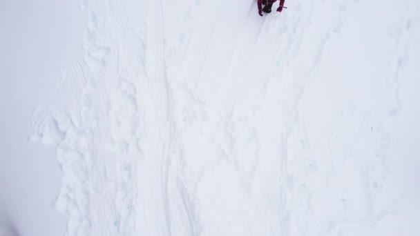 空中俯瞰着一个小孩滑落在积雪覆盖的山丘上的景象 高质量的4K镜头 — 图库视频影像