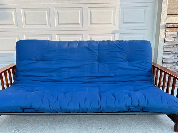 stock image futon and frame on the sidewalk driveway of a house for free pickup . High quality photo