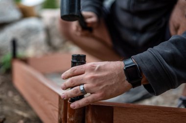 Yükseltilmiş bir yatak bahçesi panelini birleştirmek için kauçuk bir çekiçle sınır kazığını kullanıyormuş. Yüksek kalite fotoğraf