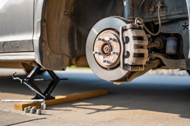 Lastik krikosuyla kaldırılmış bir aracın tekerleği. Paslı gövde ve destek görünür durumda. Yüksek kalite fotoğraf