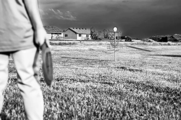 stock image Selective focus fairway grass with a defocused young child holding a putter disc and golf goal in the distance. . High quality photo