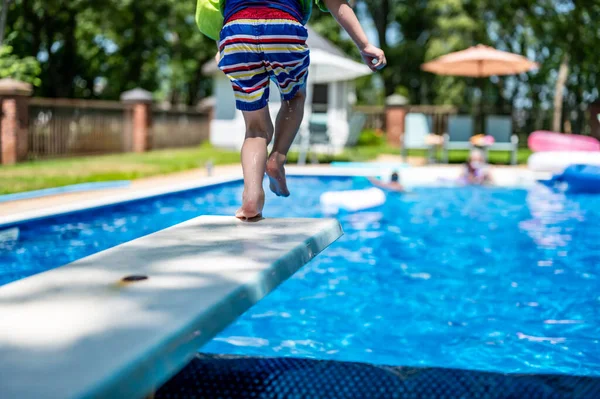 Selective focus on a swimming board as a young boy jumps into a pool. . High quality photo