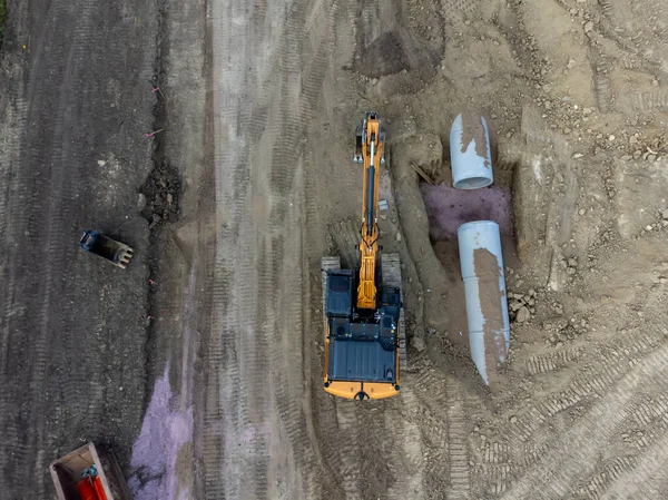 Excavator next to an open trench with two culverts ready for a connection juncture. . High quality photo