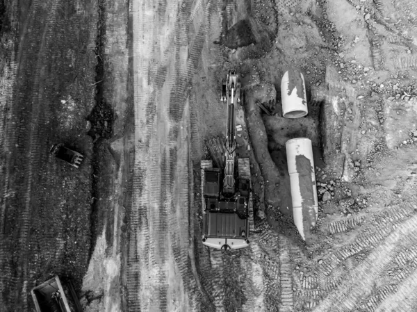 Excavator next to an open trench with two culverts ready for a connection juncture. . High quality photo