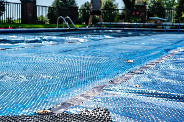 Retractable floating pool cover to keep out leaves and keep in heat being pulled back from water. . High quality photo