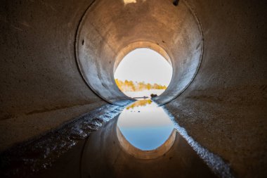 Inside a circular concrete drainage culvert with a trickle of water. High quality photo clipart