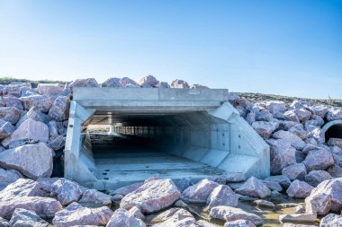 Yığının ortasında bir açıklık gösteren büyük bir kaya yığınını kesen bir tünel. Tünel insan yapımı gibi görünüyor, muhtemelen taşıma ya da madencilik amaçlı, engebeli ve pürüzlü ortadaki