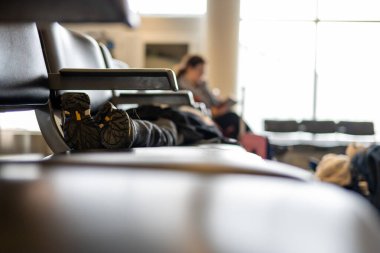 Selective focus on the feet of a child asleep on a row of chairs in an airplane terminal . High quality photo clipart