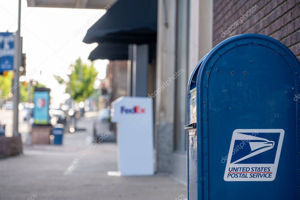 Sioux Falls, South Dakota, USA - 5.15.2025: Selective focus on a USPS mailbox with a defocused FedEx mailbox in the distance. High quality photo