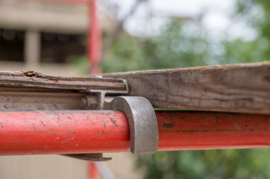 Gündüz saatlerinde bir inşaat sahasında kurulmuş tahta levhalarla güvenli bir bağlantı gösteren metal iskelenin yakın görüntüsü..