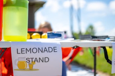 Canlı bir topluluk toplantısında parlak renkli limonata standı ziyaretçileri cezbediyor. Sıcak bir gün insanları tatlı içeceklerin ve dostluğun tadını çıkarmak için bir araya getiriyor..