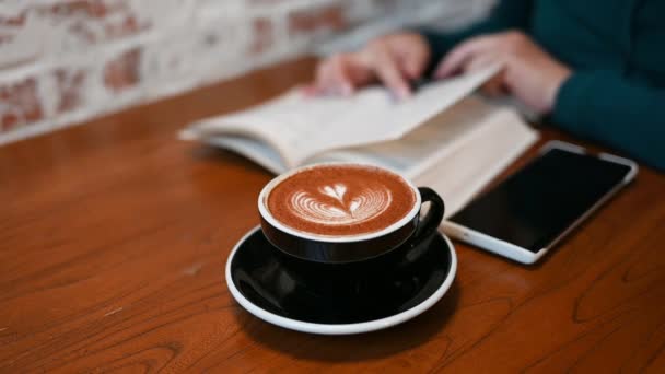 Tuğla Duvarın Yanındaki Ahşap Masada Bir Fincan Kahveyle Kitap Okuyan — Stok video