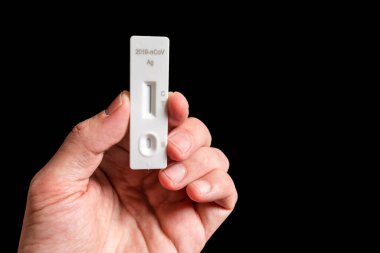 Siyah bir arkaplanda Covid-19 otomatik yakın çekim görüntüsü tutuyor.