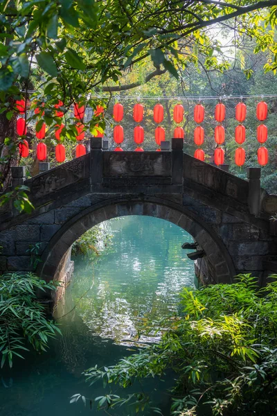 Stone arch bridge and red Chinese lanterns above a pond in Jinli, Chengdu, Sichuan province, China