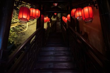 Geleneksel Çin feneriyle aydınlatılmış ahşap merdiven loş bir alana çıkıyor, kültürel mimari sergileniyor..