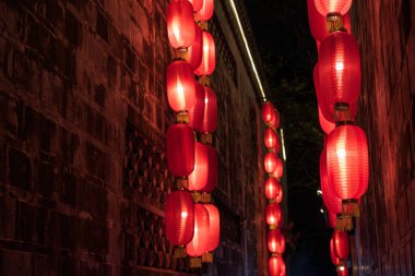 Bir dizi kırmızı Çin feneri dar bir sokak boyunca aydınlanır ve canlı ve şenlikli bir atmosfer yaratır..