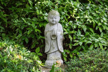 Yeşilliklerle çevrili meditasyon pozisyonunda bir Buda heykeli Çin maneviyatının sükunetini yakalıyor..