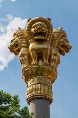 Şaşılacak derecede görkemli bir altın aslan sermaye heykeli, Çin 'deki Şangay tapınağındaki açık mavi gökyüzünün altında zarif bir şekilde bir sütunun üzerinde duruyor.