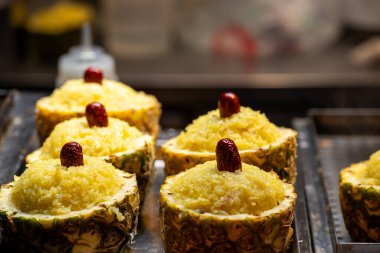 Bu güzel sunulan ananas tatlılar ustalıkla yapışkan pirinçle doldurulur ve üzeri lezzetli kırmızı hurma ile kaplanır.