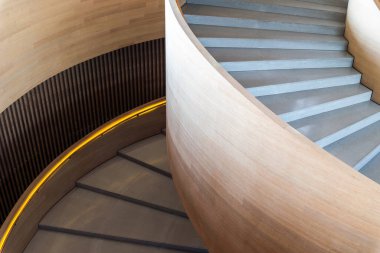 Modern spiral merdiven. Merdiven pürüzsüz, açık renkli ahşapla yapılmış, parlak ve zarif bir görünüm yaratıyor. Basamaklar betondan yapılmış, zıt dokular eklenmiş.