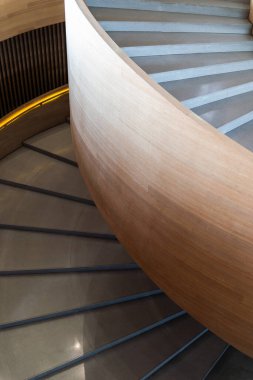 Modern spiral merdiven. Merdiven pürüzsüz, açık renkli ahşapla yapılmış, parlak ve zarif bir görünüm yaratıyor. Basamaklar betondan yapılmış, zıt dokular eklenmiş.