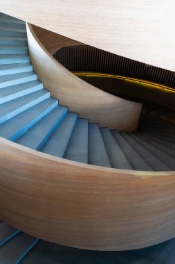 Modern spiral merdiven. Merdiven pürüzsüz, açık renkli ahşapla yapılmış, parlak ve zarif bir görünüm yaratıyor. Basamaklar betondan yapılmış, zıt dokular eklenmiş.