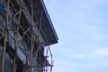 Sabahları açık mavi gökyüzüne karşı bambu merdiveni olan bir bina..